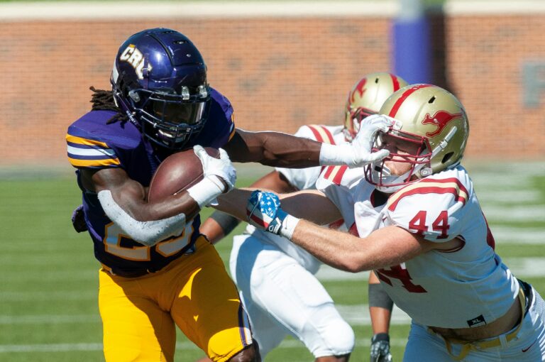 Dynamic on-field action of tackling during an American football game.