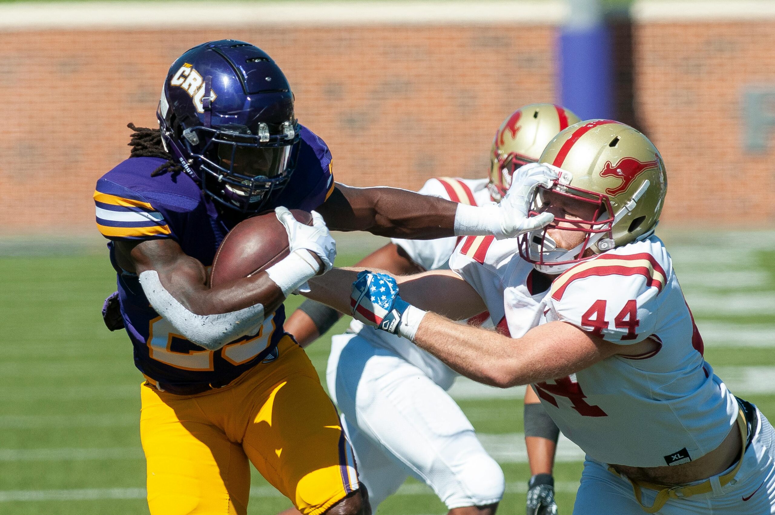 Dynamic on-field action of tackling during an American football game.